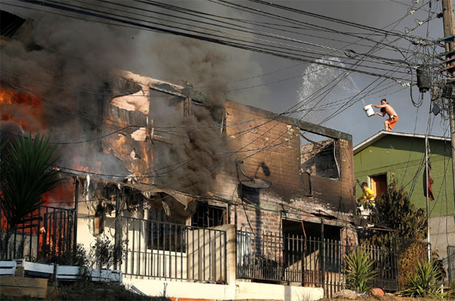 Người dân cố gắng dập lửa đang phá hủy ngôi nhà từ đám cháy rừng.