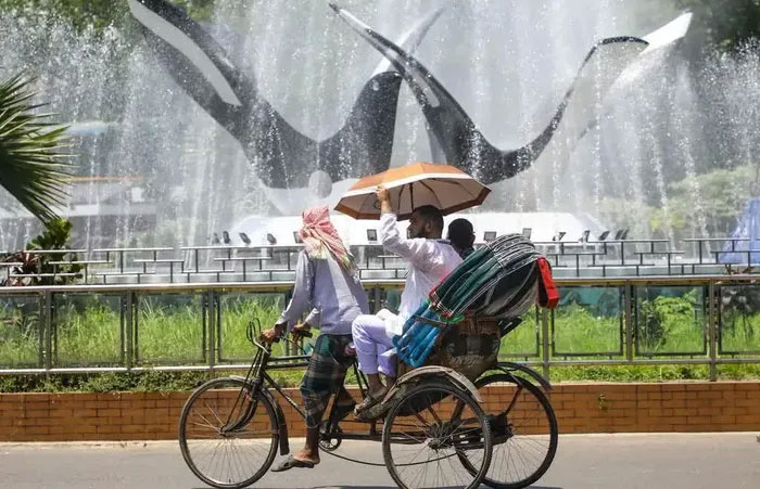 Một chiếc xe kéo đi ngang qua đài phun nước trong đợt nắng nóng đang diễn ra ở Bangladesh