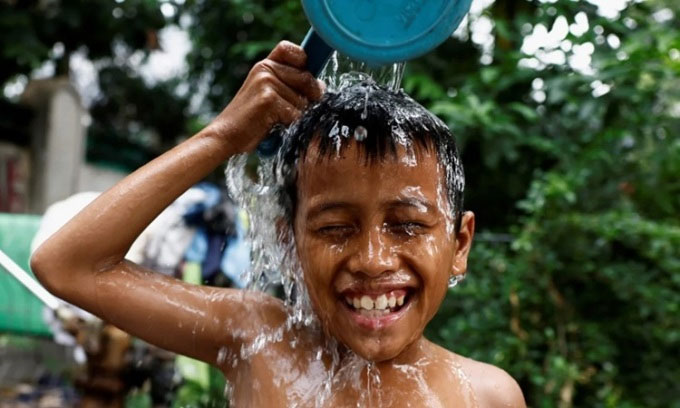 Một bé trai đổ nước lên đầu để giải nhiệt ở khu vực đông dân ở Jakarta hôm 16/5/2024.