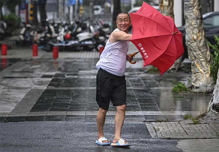 Một người đi bộ đi ngược gió trên phố ở Hải Khẩu, tỉnh Hải Nam, miền Nam Trung Quốc